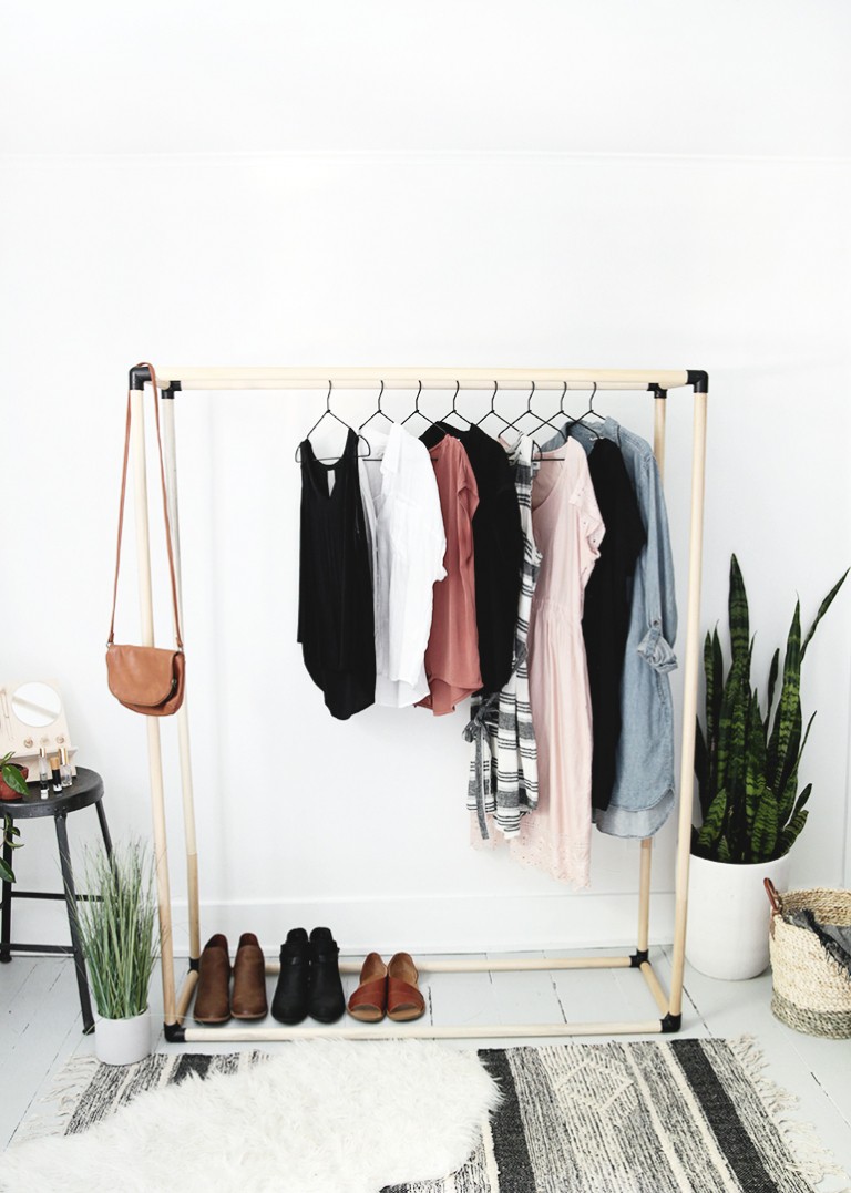 black and wood dowel clothing rack with clothes on it
