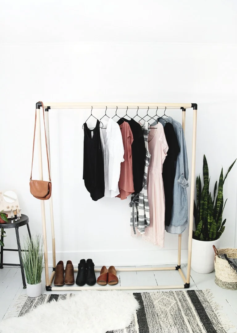 black and wood dowel clothing rack with clothes on it