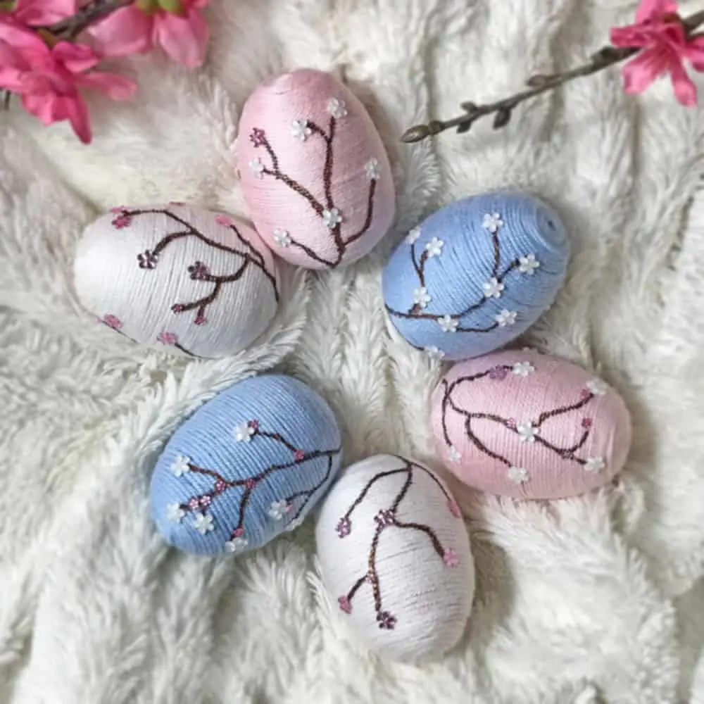 Decorative easter eggs wrapped with yarn with cherry blossoms