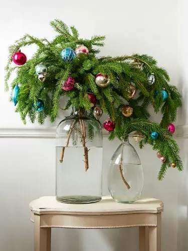 This may contain: two glass vases with christmas ornaments on top of a table next to a wall